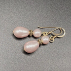 Pair of pink pearl earrings with gold accents on a gray background