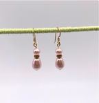 Pair of pink pearl earrings on a thin rod against a light background