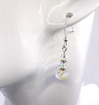 A single dangling earring displayed on a white mannequin ear. The earring has a sterling silver fishhook back with three faceted iridescent clear crystal beads refracting colors from the environment.