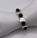 A beaded bracelet displayed on a white mannequin wrist. The bracelet features dark brown fuzzy mgambo beads and white mother-of-pearl butterfly-shaped beads.