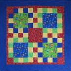 A baby quilt pattern with a colorful patchwork design featuring blue, green, red, and cream sections, surrounded by a solid blue border.