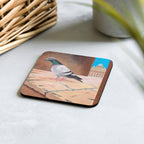 single coaster with a pigeon standing on a stone shelf with the Vatican in the background. A basket is in the upper left hand corner of the picture